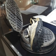 A pair of Nike shoes from 1972 with the waffle tread sole, sitting atop a waffle iron
